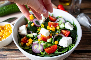 A green vegan salad made from a mix of green leaves and vegetables. On a wooden background