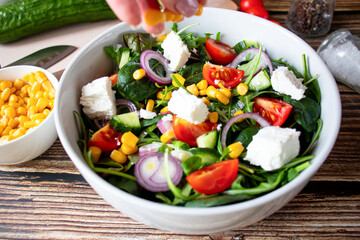 A green vegan salad made from a mix of green leaves and vegetables. On a wooden background