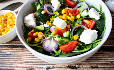 A green vegan salad made from a mix of green leaves and vegetables. On a wooden background
