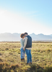 Love, interracial and couple on countryside vacation, holding hands and joyful outside with romantic view. Romance, happy man and black woman on field, holiday and weekend break, happiness or support