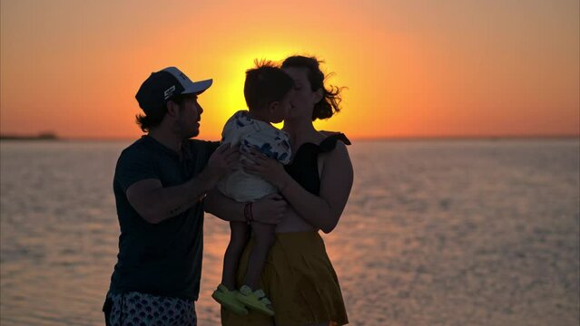 Young couple with their little toddle enjoying a beautiful sunset at a lagoon near cancun mexico called isla blanca