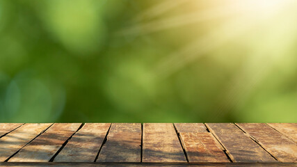 Fototapeta premium Wooden table top with natural green blurred background or various leaves, fresh bright sunlight, product empty concept.