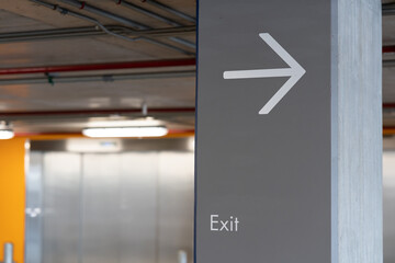 Arrow pointing to the exit on the pole. Exit Sign, Metal Exit Sign, Parking Exit in Condo. Symbol. copy space. selective focus. - obrazy, fototapety, plakaty