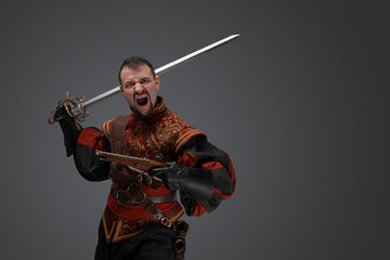 Shot of attacking conquistador with sword dressed in red costume.