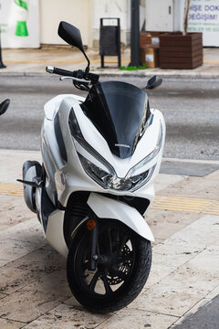 Side, Turkey -January 27, 2023:    A  black motorcycle stands in a parking against the backdrop of street