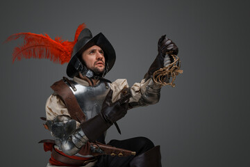 Shot of conquistador with plumed helmet and plate armor holding broken epee.