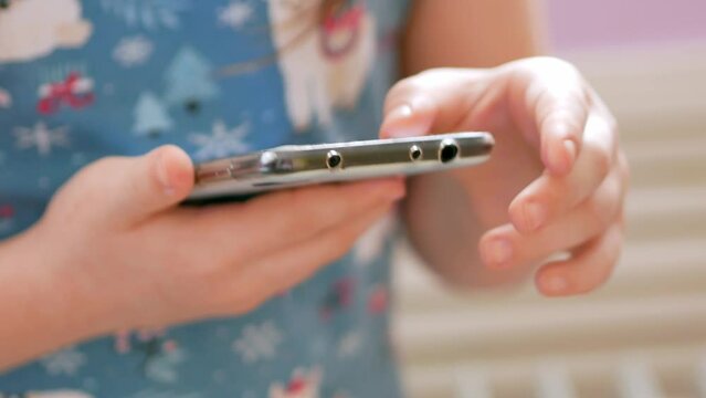 The child holds the phone, presses the buttons on the end of the smartphone, takes a screenshot, searches for information on the Internet.