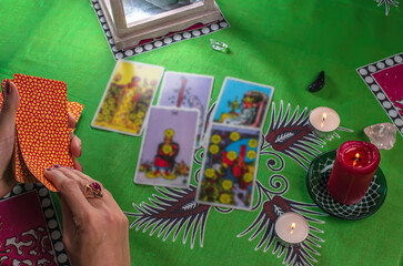 Divination by tarot cards on a background of a green tablecloth with burning candles. Selective focus.