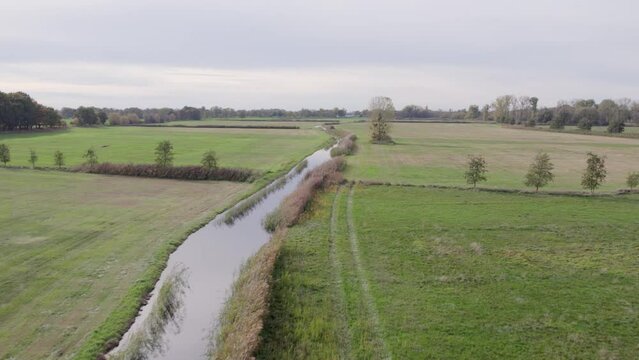Drone footage of place called Uetz in Brandenburg, Germany. Autumn colors and atmosphere, steady horizontal flight over water channel running through fields.