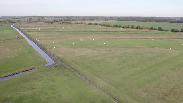 Areal drone footage of water channel and vast farming fields with autumn colors taken at place called Uetz in Brandenburg, Germany. Peaceful and tranquil atmosphere in rural farm lands.