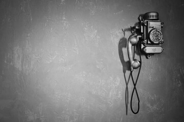 Antique wired telephone for communication hangs on textured gray wall, toned image. Old vintage phone from past for backgrounds. Concept of communicate and telegraph. Copy text space for advertising