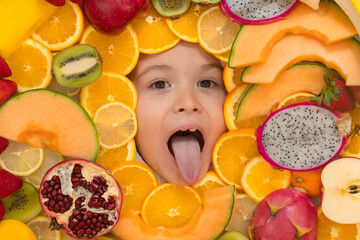 Fototapeta na wymiar Kid licking orange. Healthy food background. Studio photo of different fruits with excited kids face. Mix of different fruits and berries. Cute little boy eats fruits. Open mouth, tongue out funny