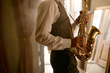Cropped shot of unrecognizable male musician playing his saxophone at home