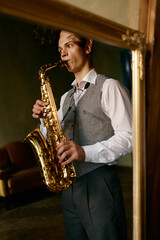 Young man playing saxophone in reflection of mirror at home