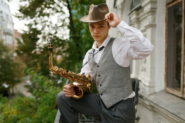 Portrait of young musician holding saxophone musical instrument