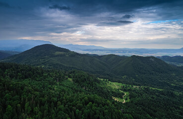 Aerial view of a beautiful landscape from Bucegi mountains in Romania, with forest green trees and cloudy sky. Travel to Romania.