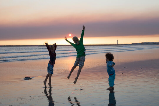 Three kids jumping on beach during sunset, Viana do Castelo, Norte Region, Portugal