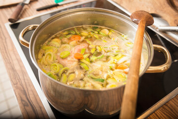 Chicken soup boiling with leek and carrot in a pot on stove, Munich, Bavaria, Germany