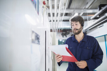 Young male engineer wearing headset and working in an industrial plant, Freiburg im Breisgau, Baden-Württemberg, Germany