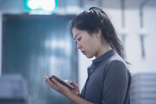Young female engineer using digital tablet in an industrial plant, Freiburg im Breisgau, Baden-Württemberg, Germany