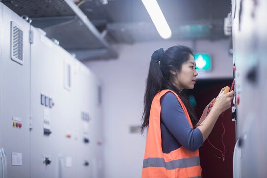 Young female engineer examining control panel with multimeter in an industrial plant, Freiburg im Breisgau, Baden-W&uuml;rttemberg, Germany
