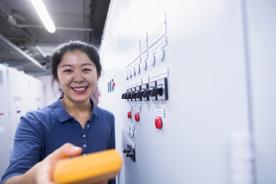 Young female engineer examining control panel with multimeter in an industrial plant, Freiburg im Breisgau, Baden-W&uuml;rttemberg, Germany