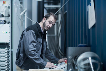 Young male engineer updating control panel in control room, Freiburg Im Breisgau, Baden-Württemberg, Germany