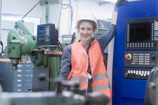 Young female engineer standing at CNC machine in an industrial plant, Freiburg im Breisgau, Baden-W&uuml;rttemberg, Germany