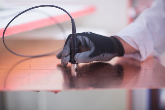 Close-up of human hand examining circuit board in industry, Hanover, Lower Saxony, Germany