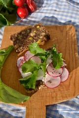  close up toast with radish slices and arugula leaves on wooden cut board