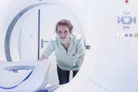 Smiling nurse looking CAT scan machine