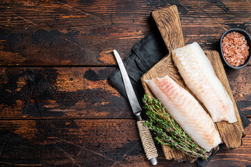 Cod fish fillets, raw codfish with thyme on wooden board. Wooden background. Top view. Copy space