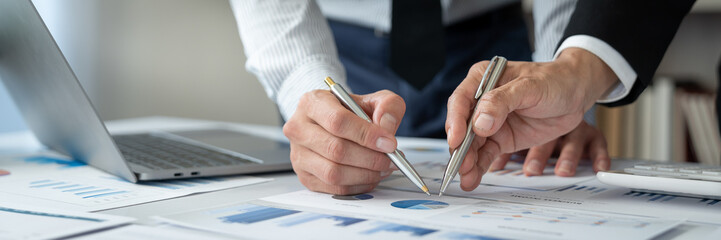 Asian businessmen and investors brainstorm applications for web design planning and develop templates, graphs, and calculations for mobile projects working together in the office.