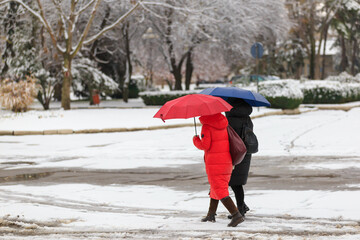 People with umbrellas during wet snow. Winter background, selective focus