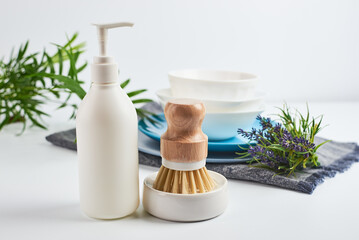 eco-friendly dishwashing brushes with organic bristles and wooden handle next to dishwashing...