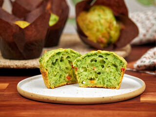 Homemade savory muffins with spinach, red bell paper and feta, in brown paper muffin liners, on a ceramic plate