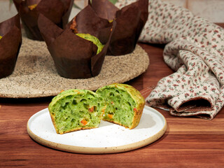 Homemade savory muffins with spinach, red bell paper and feta, in brown paper muffin liners, on a ceramic plate