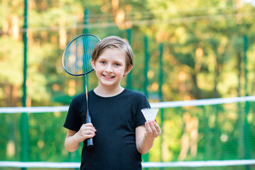 smiling little sportsman playing badminton. joyful child holds a badminton racket 