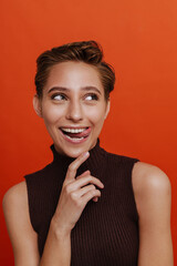 Fototapeta premium Young beautiful short-haired happy woman touching her chin showing tongue