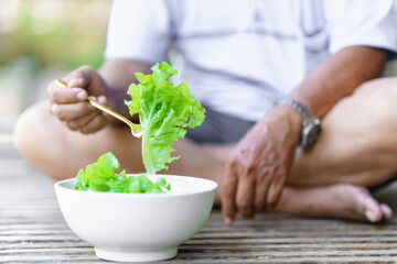 Man's hand picking up lettuce with a fork from a white bowl.. Healthy food concept.