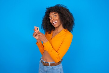 Nice addicted cheerful young beautiful brunette woman wearing colourful dress over white wall using...