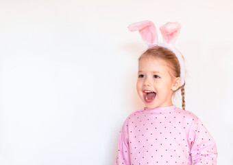 smiling little child girl with Easter bunny ears in pink jacket on white background, copy space