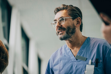 Low angle view of smiling mature male doctor wearing eyeglasses at hospital