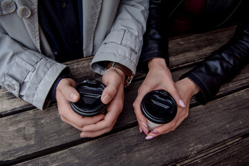 The guy and the girl are holding takeaway coffee in their hands. Date in a cafe