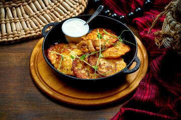 Traditional Ukrainian deruny with sour cream in a black pan. Ukrainian cuisine Potato pancake