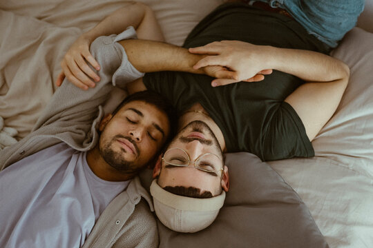 High angle view of gay couple sleeping on bed at home