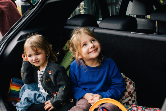 Smiling girls sitting together in electric car trunk