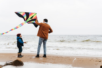 Father and his son playing with kite on the beach
