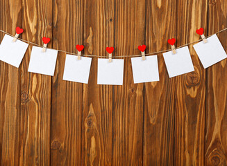 white pieces of paper on clothespins with a heart on a wooden background