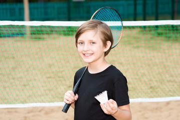 smiling little sportsman playing badminton. joyful child holds a badminton racket